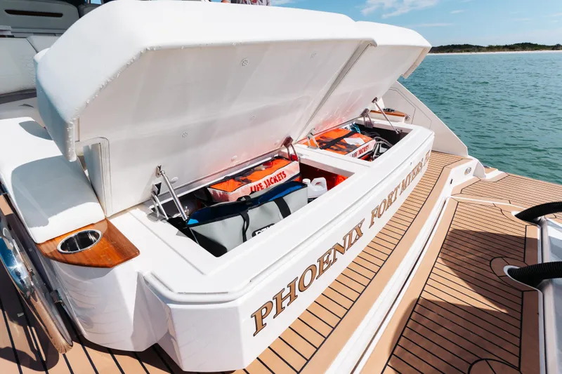 Phoenix Yacht Photos Pics 2023 Tiara 48 yacht storage compartment with life jackets, docked on calm water.