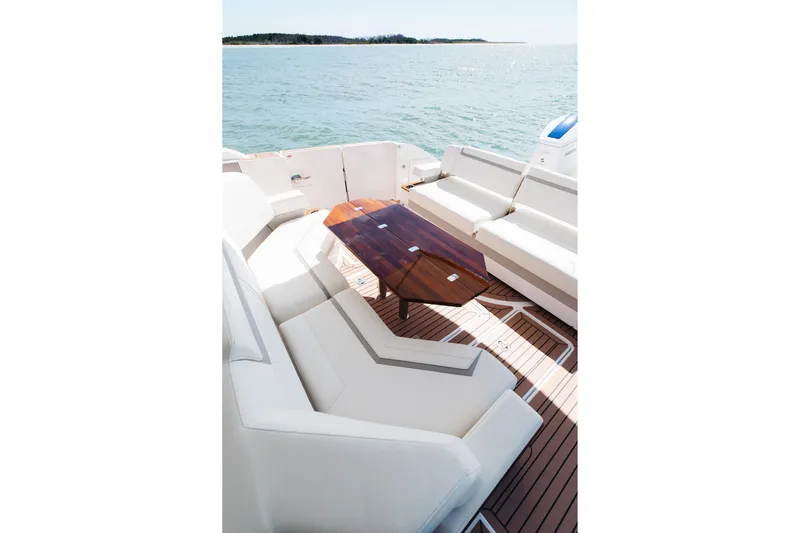 Phoenix Yacht Photos Pics Luxurious 2023 Tiara 48 yacht deck with elegant seating and wooden table, overlooking serene waters.