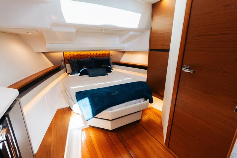 Phoenix Yacht Photos Pics Luxurious cabin interior of 2023 Tiara 48 yacht with elegant wood finishes and cozy bedding.