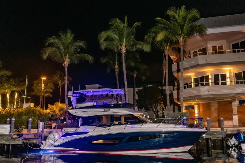Syren Yacht Photos Pics 2022 Regal 42 FXO yacht docked at night, illuminated by blue lights.