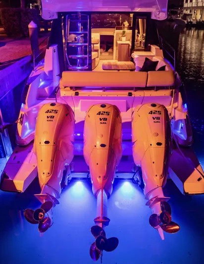 Syren Yacht Photos Pics 2022 Regal 42 FXO boat with triple outboard engines, illuminated by blue lights at night.