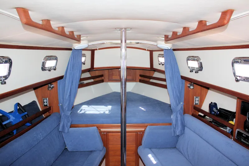 Tigerlily Yacht Photos Pics Interior of 2004 Pacific Seacraft 31 sailboat with blue upholstery and wooden accents.