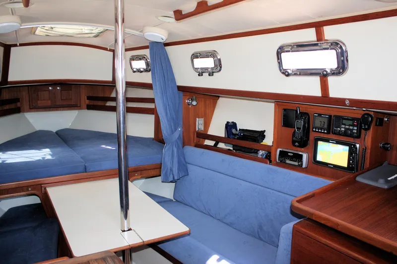 Tigerlily Yacht Photos Pics Interior of 2004 Pacific Seacraft 31 sailboat with blue seating and navigation equipment.