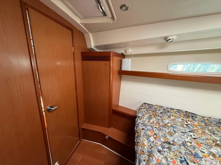 Deep Unreal Yacht Photos Pics Interior cabin of 2008 Beneteau Oceanis 40 sailboat with wooden finish and patterned bedding.
