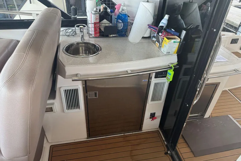  Yacht Photos Pics 2016 Regal 46 Sport Coupe yacht kitchenette with sink, mini fridge, and countertop essentials.