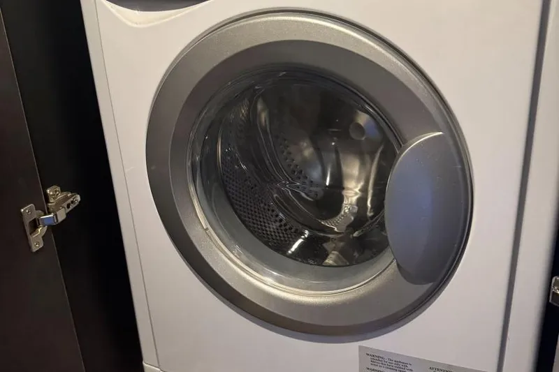  Yacht Photos Pics Front-loading washing machine in a compact space, partially open cabinet door.