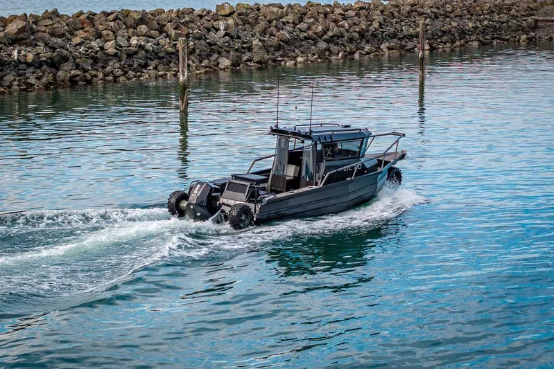  Yacht Photos Pics 2024 StabiX 240UCC boat navigating calm waters near rocky shoreline.