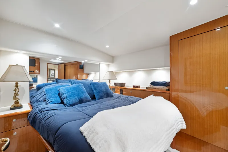 Walk West Yacht Photos Pics Luxurious bedroom interior of a 2001 Viking Convertible yacht with blue bedding and wooden accents.