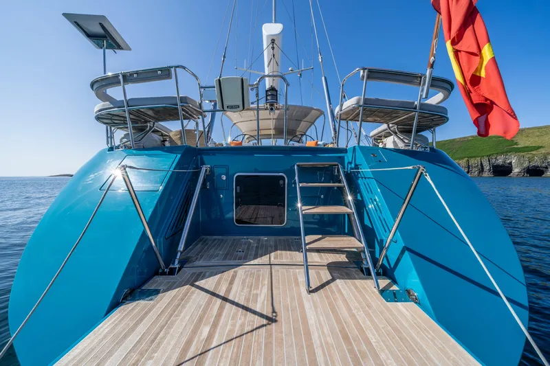 Karibu Yacht Photos Pics Luxurious 2013 Oyster 885 yacht with blue deck, ladder, and red flag, sailing in calm waters.