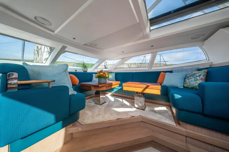 Karibu Yacht Photos Pics Luxurious interior of 2013 Oyster 885 yacht with blue seating and wooden table.