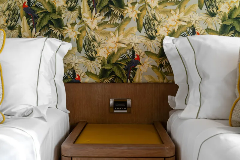Karibu Yacht Photos Pics Tropical-themed bedroom with floral wallpaper, white bedding, and wooden nightstand.