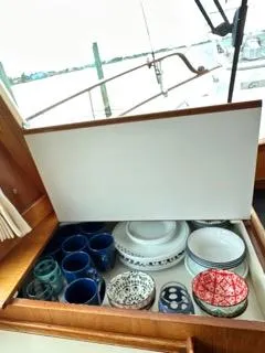 Its About Time Yacht Photos Pics 1996 Grand Banks Classic yacht kitchen drawer with assorted dishes and mugs.