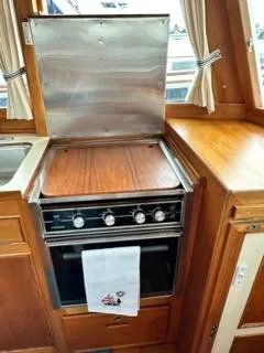 Its About Time Yacht Photos Pics 1996 Grand Banks Classic yacht kitchen with stove, wooden cabinetry, and curtains.