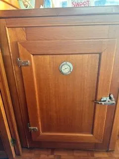 Its About Time Yacht Photos Pics Wooden cabinet door with a round gauge, aboard a 1996 Grand Banks Classic.