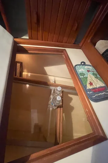  Yacht Photos Pics Interior of 1995 Island Packet 40 sailboat with open wooden cabinet and water bottles.