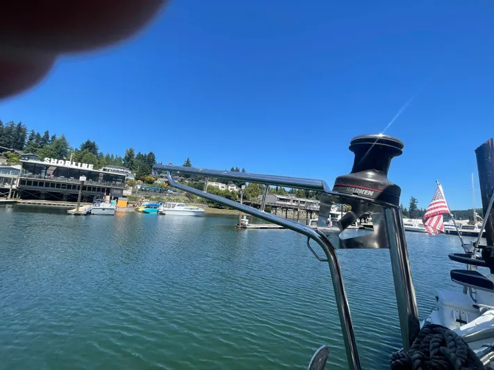  Yacht Photos Pics Island Packet 40 sailboat in marina, American flag, clear blue sky, shoreline buildings.