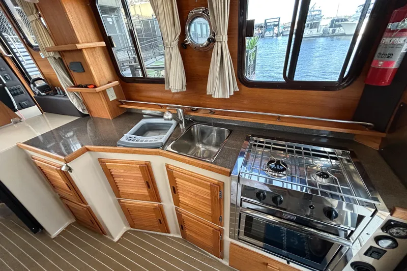  Yacht Photos Pics 2017 Ranger Tugs R-31 CB interior kitchen with stove, sink, and wooden cabinetry.
