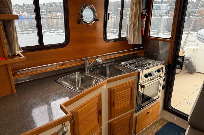  Yacht Photos Pics 2017 Ranger Tugs R-31 CB interior kitchen with sink, stove, and wooden cabinetry.