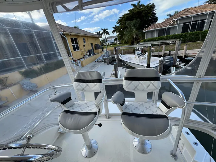  Yacht Photos Pics Riviera 40 Convertible 2002 yacht cockpit with two cushioned chairs, docked near waterfront homes.