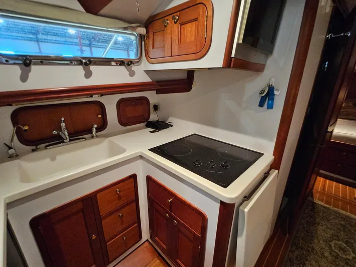 Lady One Yacht Photos Pics 2003 Legacy 40 Hardtop Express yacht kitchen with stove, sink, and wooden cabinetry.