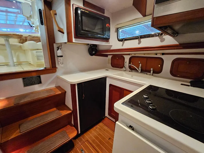 Lady One Yacht Photos Pics 2003 Legacy 40 Hardtop Express yacht kitchen with stove, microwave, and wooden cabinetry.