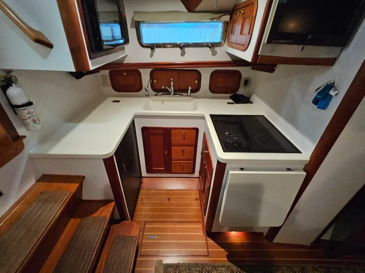 Lady One Yacht Photos Pics 2003 Legacy 40 Hardtop Express yacht kitchen with stove, sink, and wooden cabinetry.