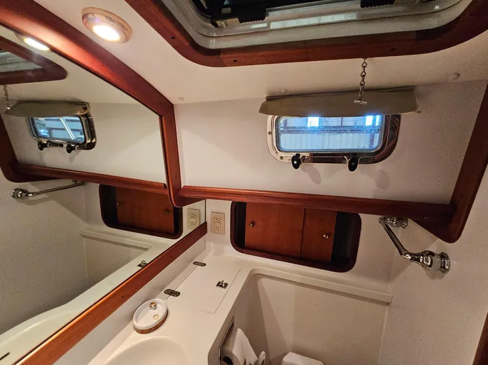 Lady One Yacht Photos Pics 2003 Legacy 40 Hardtop Express yacht bathroom with wooden accents and porthole window.