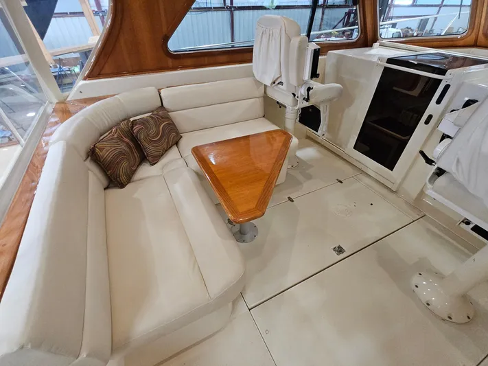 Lady One Yacht Photos Pics Interior of 2003 Legacy 40 Hardtop Express with white seating and wooden table.