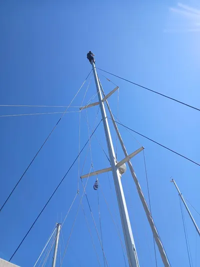  Yacht Photos Pics Person atop mast of 2009 Lagoon 440 sailboat against clear blue sky.