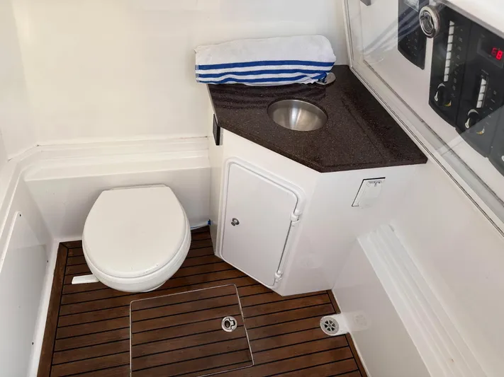  Yacht Photos Pics 2017 Custom Carolina Center Console boat bathroom with toilet, sink, and wooden flooring.