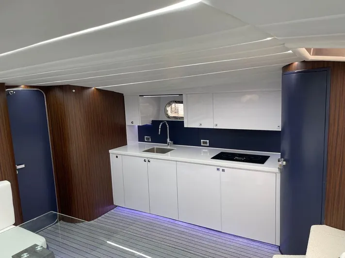 Marchese Yacht Photos Pics Modern kitchen area in a 1984 Magnum Marine boat with sleek white cabinets and blue accents.