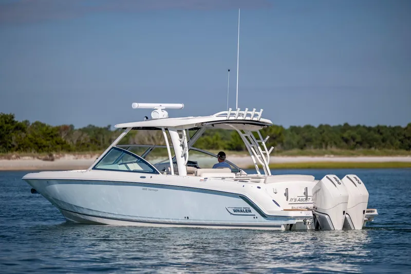  Yacht Photos Pics 2023 Boston Whaler 320 Vantage boat cruising on calm water near a shoreline.