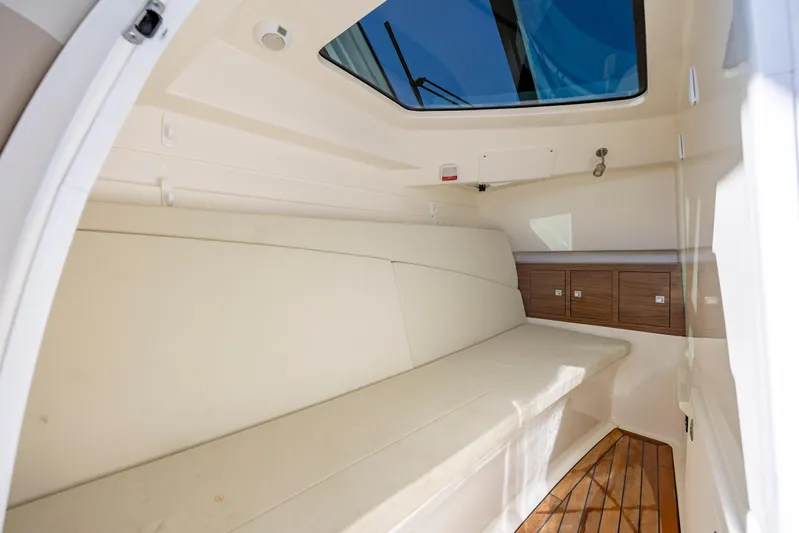  Yacht Photos Pics 2023 Boston Whaler 320 Vantage cabin interior with cushioned seating and wooden flooring.
