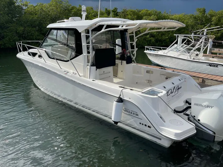  Yacht Photos Pics 2020 Boston Whaler 325 Conquest boat docked in a marina, surrounded by lush greenery.
