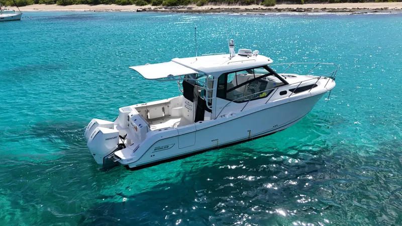  Yacht Photos Pics 2020 Boston Whaler 325 Conquest boat on clear turquoise water near a sandy shore.