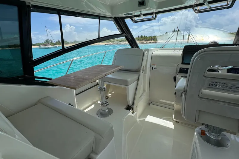  Yacht Photos Pics Interior of 2020 Boston Whaler 325 Conquest boat with seating and table, overlooking turquoise water.