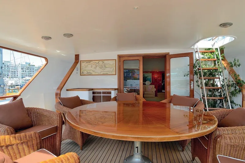 Madame Thelma Yacht Photos Pics Luxurious 1975 CRN Ancona Navetta 40 yacht interior with elegant wooden table and wicker chairs.