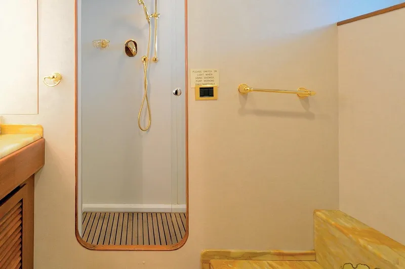 Madame Thelma Yacht Photos Pics Luxurious yacht bathroom with gold fixtures, wooden accents, and a modern shower.