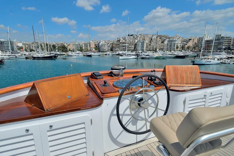 Madame Thelma Yacht Photos Pics Helm of 1975 CRN Ancona Navetta 40 yacht overlooking marina with cityscape background.