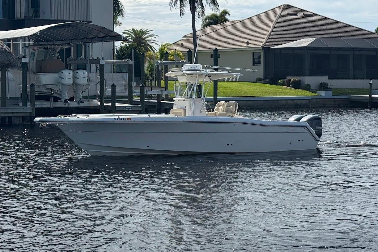 2014 Stamas 317 Tarpon boat on calm water near a dockside home.