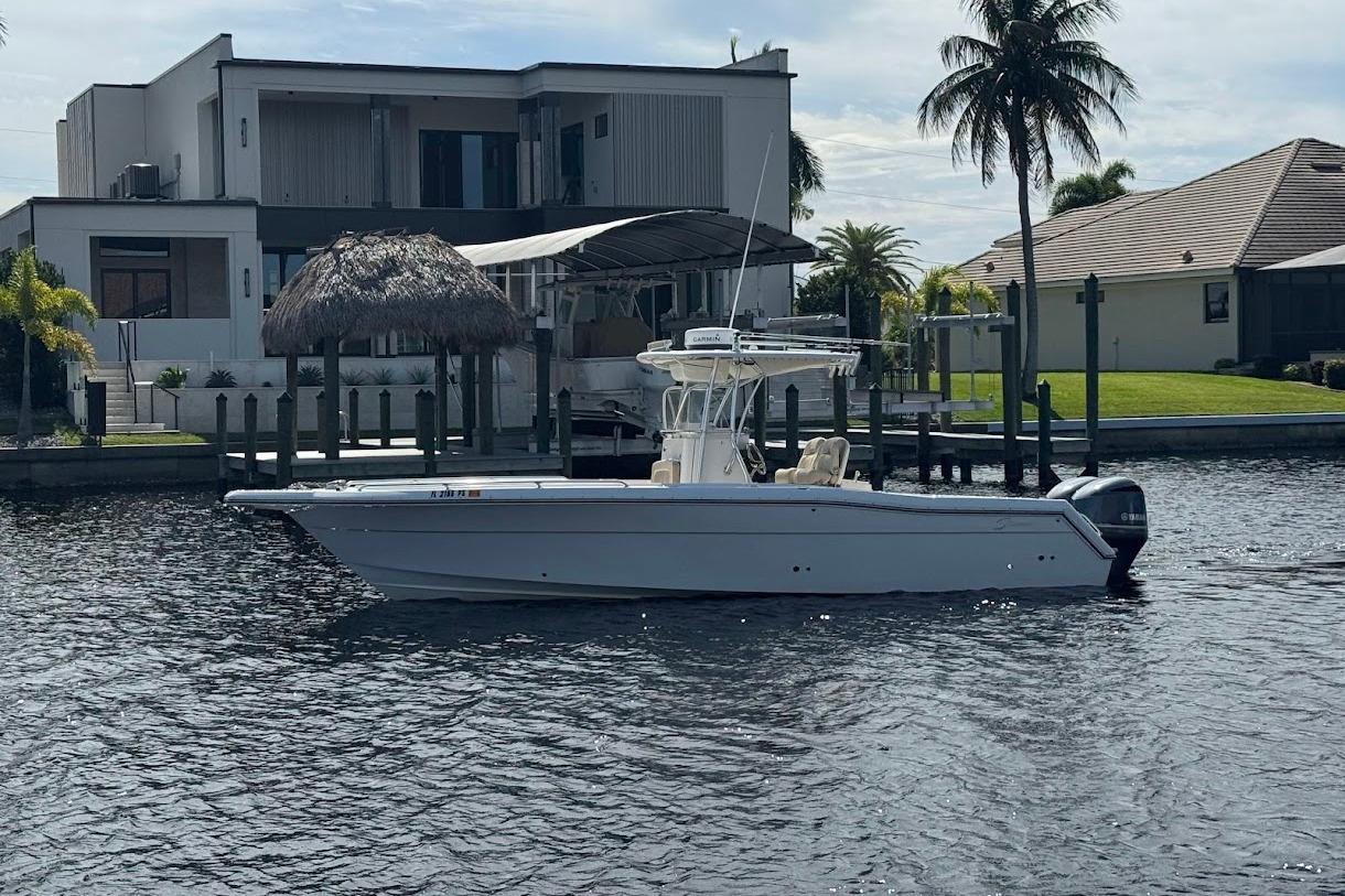 2014 Stamas 317 Tarpon boat on water near modern waterfront homes and palm trees.