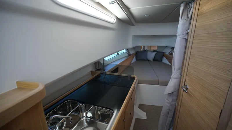 In-stock 2024 Nimbus C11 #082 Yacht Photos Pics 2024 Nimbus Commuter 11 #082 interior with kitchenette and cozy sleeping area.