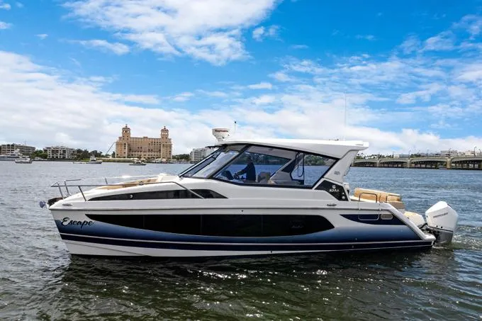 Escape Yacht Photos Pics 2022 Aquila 36 Sport yacht on water, with cityscape and blue sky background.