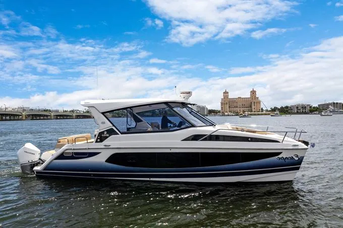 Escape Yacht Photos Pics 2022 Aquila 36 Sport boat cruising on a sunny day with cityscape background.