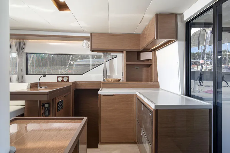  Yacht Photos Pics Modern interior of 2022 Lagoon 500 yacht with sleek wooden cabinetry and large windows.