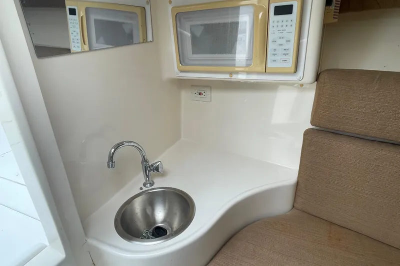 Steph-lo Yacht Photos Pics 2004 SeaVee 320i Cuddy interior with sink, microwave, and cushioned seating.