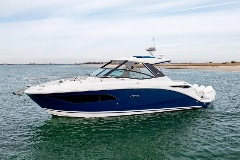  Yacht Photos Pics 2020 Sea Ray Sundancer 320 Outboard cruising on calm waters near a sandy shoreline.