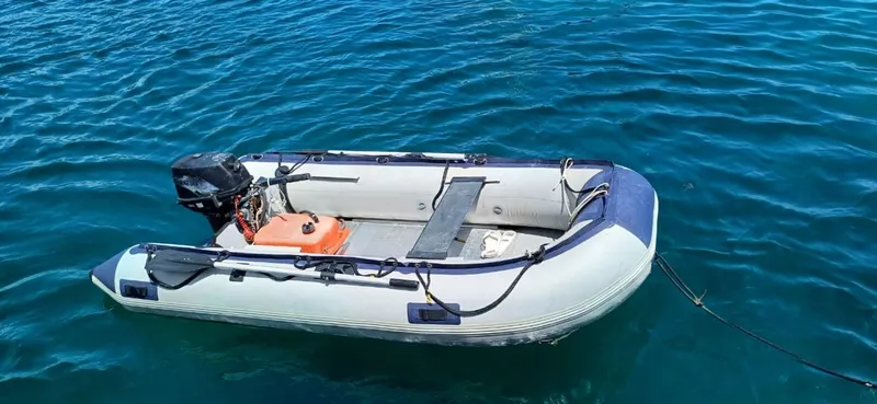  Yacht Photos Pics Inflatable dinghy with outboard motor floating on clear blue water.