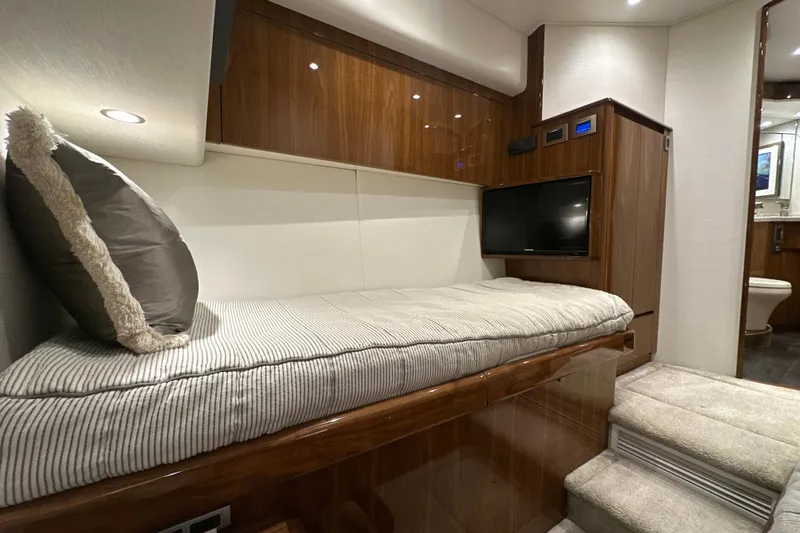 Wildcatter Yacht Photos Pics 2017 Viking 55 Convertible yacht interior with cozy bed, TV, and wooden cabinetry.