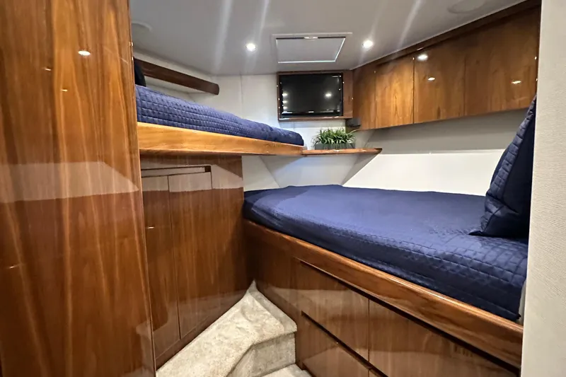 Wildcatter Yacht Photos Pics Luxurious cabin interior of 2017 Viking 55 Convertible yacht with wooden finish and blue bedding.